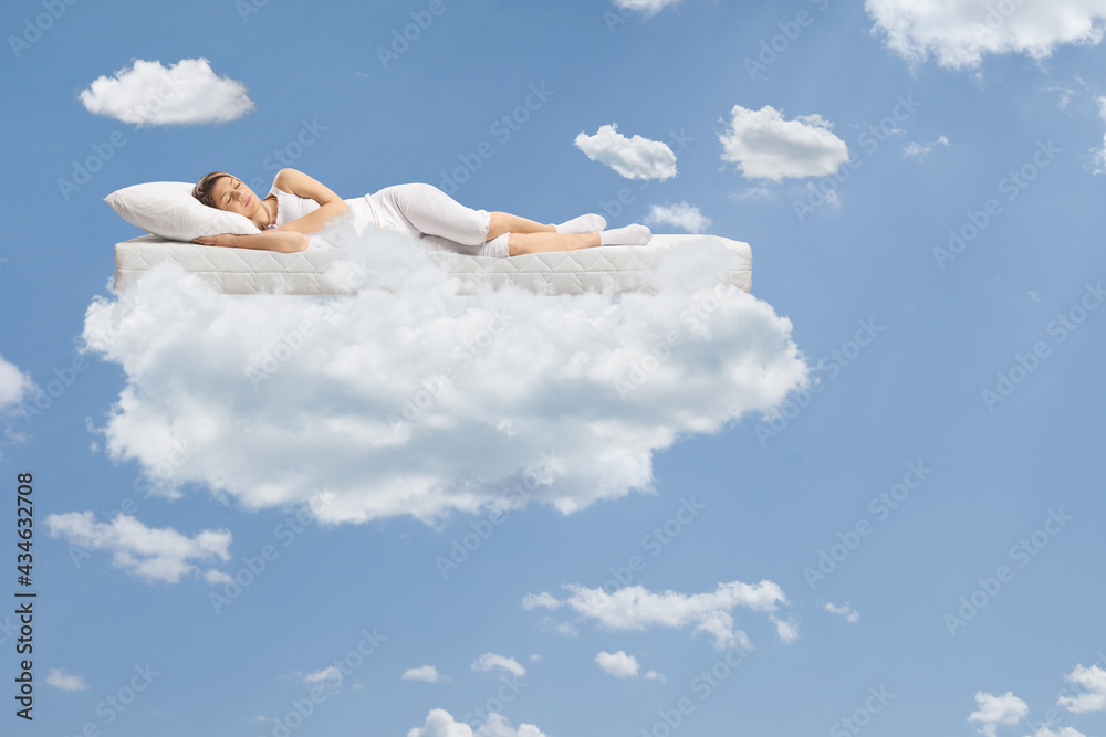 Young woman sleeping on a floating mattress up in the clouds Young woman sleeping on a floating mattress up in the clouds