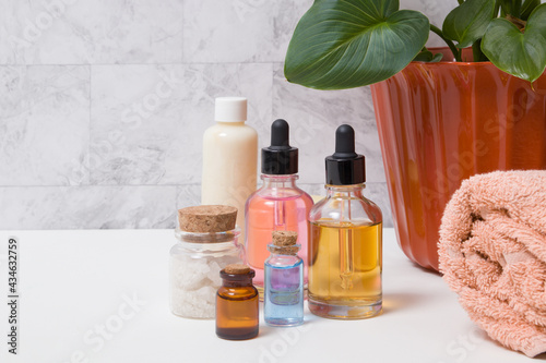 Bottles of tincture, salt, oil or serum, a towel and a plant in the bathroom. Skin care SPA concept