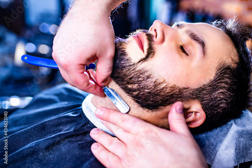 Hairstylist cutting hair of male customer at barber shop