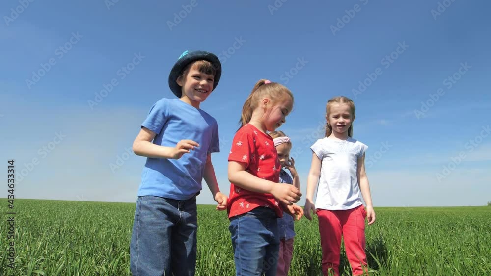 Children jump into the field and raise their hands high in the air. Happy energetic children jump in the long grass, laugh and look at the camera. Slow motion Children jump into the field and raise their hands high in the air. Happy energetic children jump in the long grass, laugh and look at the camera. Slow motion