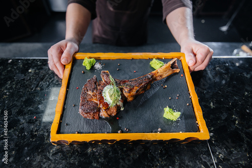 Bild auf Leinwand A professional chef beautifully serves a juicy grilled steak with butter and seasonings