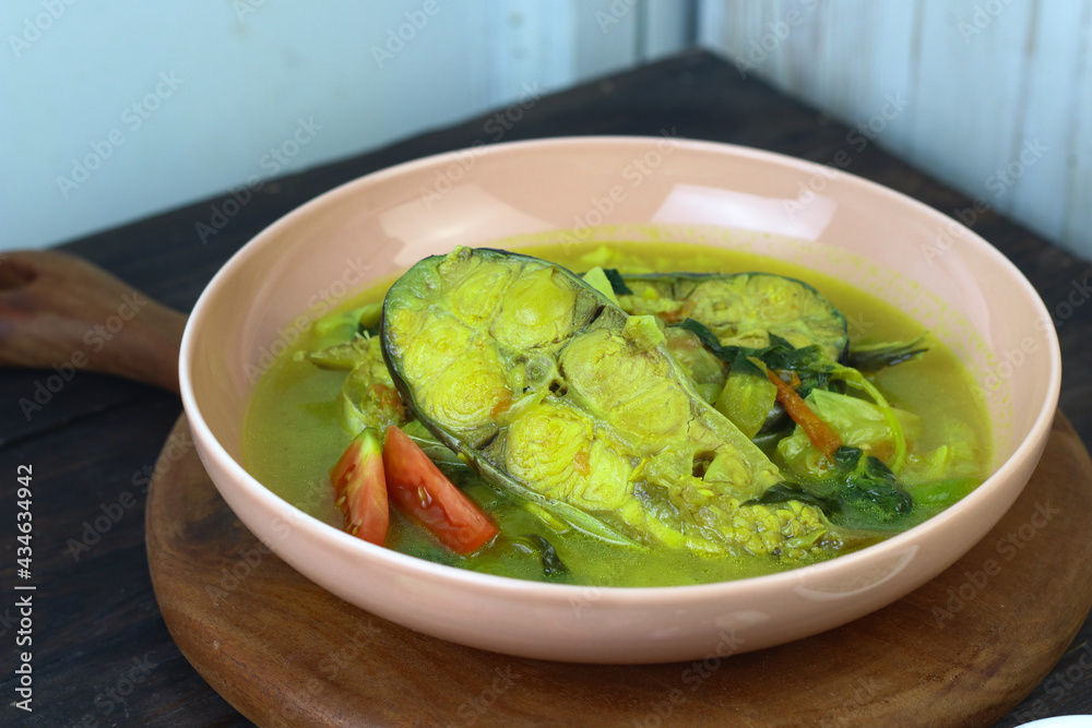 Pindang Ikan Patin or Catfish vegetables Soup , Indonesian food popular from Palembang. Served on ceramic bowl garnished wit tomato slices. Copy space for text. Dark wooden background. Pindang Ikan Patin or Catfish vegetables Soup , Indonesian food popular from Palembang. Served on ceramic bowl garnished wit tomato slices. Copy space for text. Dark wooden background.
