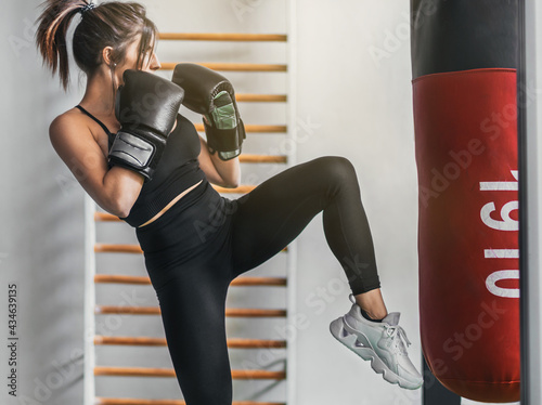 girl about to throw a kick. she is in attack position and in profile. she is wearing a ponytail and her hair up. she is practicing kick boxing. photo