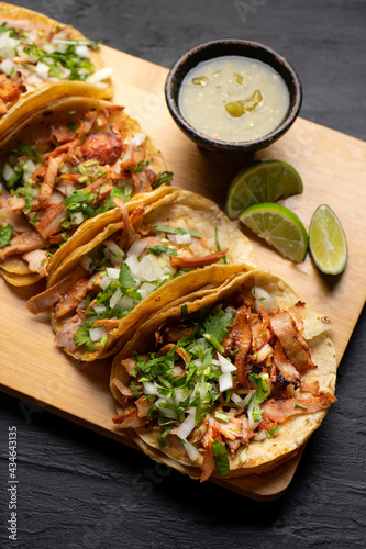 Pork tacos called al pastor with pineapple on dark background. Mexican tacos