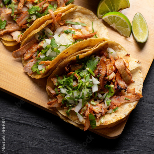Pork tacos called al pastor with pineapple on dark background. Mexican tacos