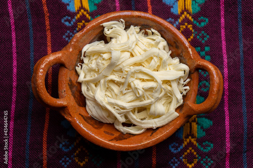 Shredded Oaxaca cheese also called quesillo on rustic background. Mexican food photo