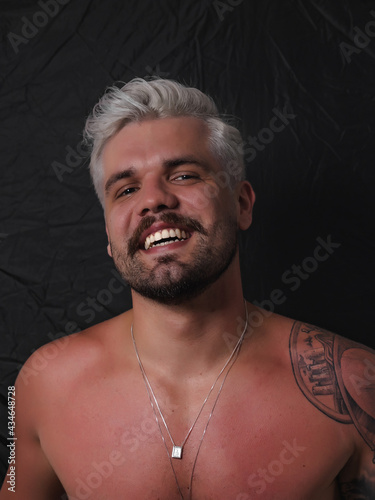 Caucasian Man Platinum Blonde White Hairstyle With Short Haircut and Moustache No Shirt and Sun Tan Gray Hair And Shoulder Tattoo