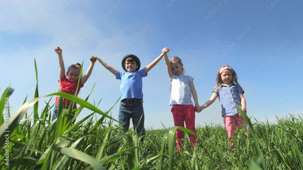 Children stand in a field holding hands, holding them high in the air and laughing. Children stand in a field in the tall grass, laughing and looking at the camera. Slow-motion Children stand in a field holding hands, holding them high in the air and laughing. Children stand in a field in the tall grass, laughing and looking at the camera. Slow-motion