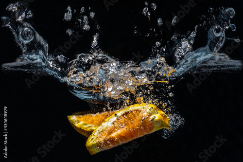 2021-04-19 ORANGE SLICES SPLASHING IN WATER WITH A BLACK BACKGROUND 