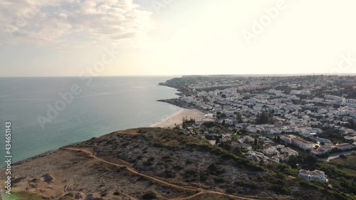 Wide revealing view over Town encircling Praia da Luz, Algarve. Aerial