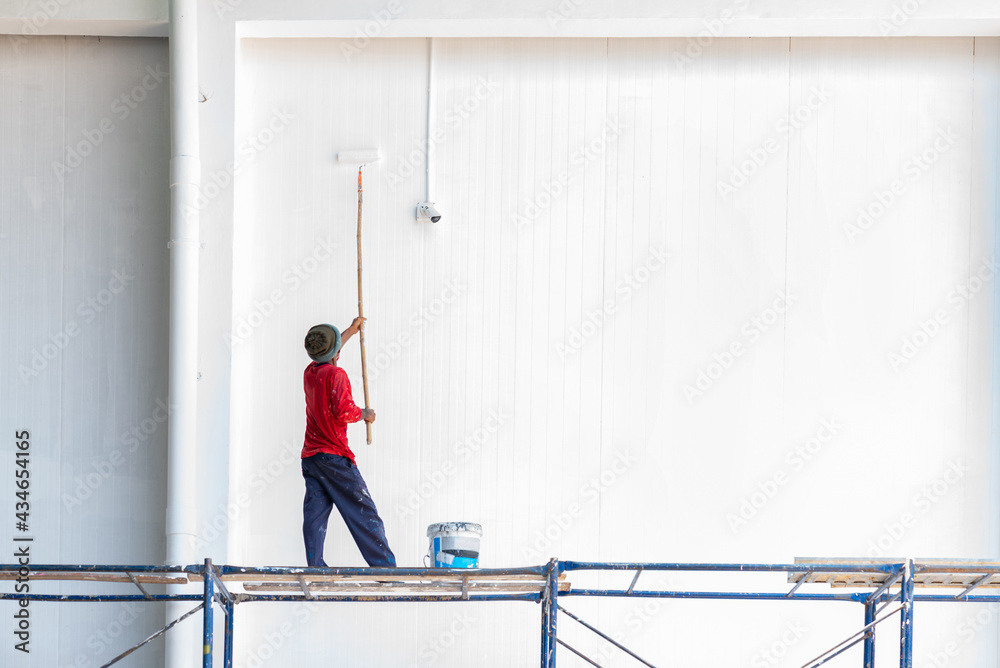 Paint Roller While Painting a factory Wall.