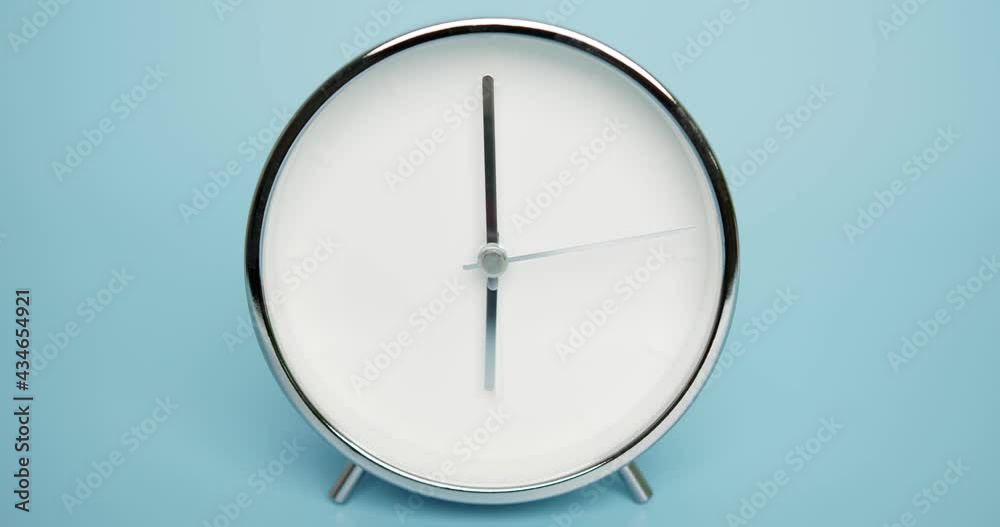 Silver Alarm clock isolated on blue background, Showtime 06.00 am or pm, Second hand minute Walk, Time concept. Silver Alarm clock isolated on blue background, Showtime 06.00 am or pm, Second hand minute Walk, Time concept.