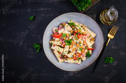 Vegetarian vegetable pasta. Pasta rigatoni with tomato, red onion, parsley and fried chickpeas with nut sauce. Vegan food. Top view, overhead