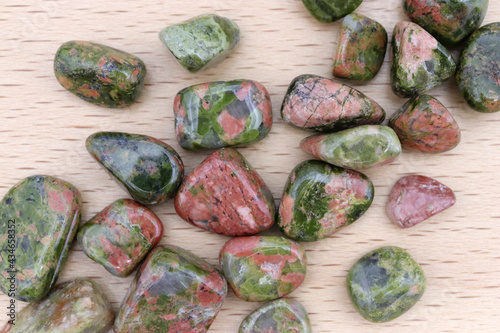 Unakite heap up jewel stones texture on light varnished wood background photo