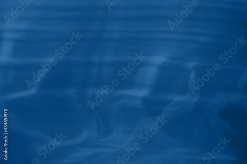 Trendy blue colored low contrast abstract background with light and shadows caustic effect. Light passes through a glass. Water background. 