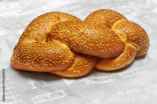 Challah - Jewish bread in Israel and at world. Inscriptions on the white tablecloth in Hebrew: Shabbat Shalom - Jewish and Israeli greetings