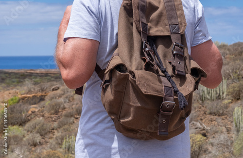 Rear view of senior man with backpack enjoying outdoors trekking, looking at horizon over sea