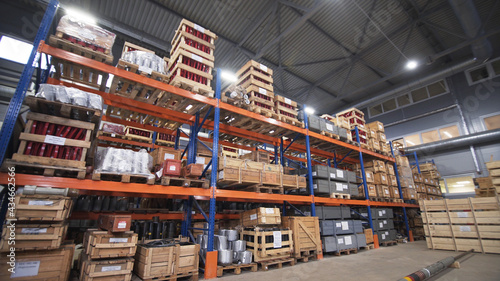 Warehouse with racks and shelves, filled with wooden boxes on pallets. Distribution products. Logistics Business. interior large warehouse with freight stacked high. Written marking on boxes