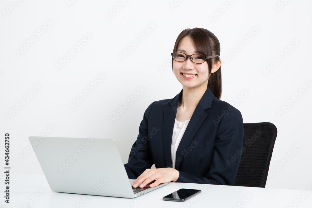パソコンで仕事をしているメガネのビジネスウーマン パソコンで仕事をしているメガネのビジネスウーマン