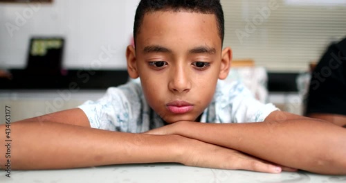 Pensive sad African descent child. Contemplative kid looking down photo