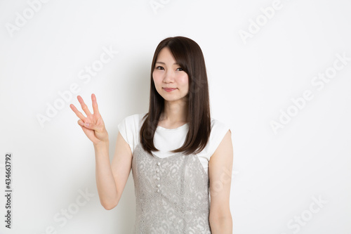 笑顔で指を3本立てている若い女性