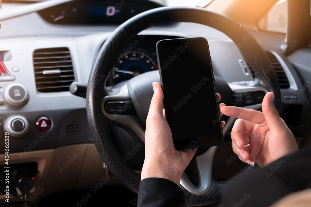 A woman sitting in front of a driver is using a mobile phone with a black screen, to see a map and use a smartphone app, to look at social media in a black car. A woman sitting in front of a driver is using a mobile phone with a black screen, to see a map and use a smartphone app, to look at social media in a black car.