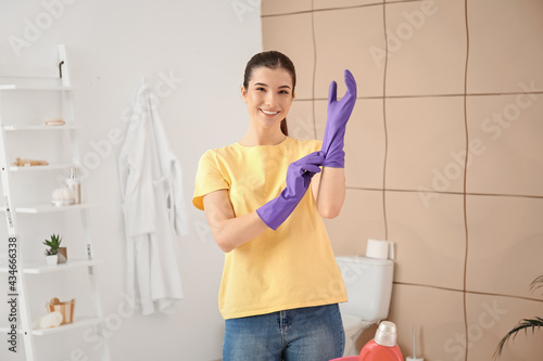 Schilderij op canvas Young woman putting on gloves in bathroom