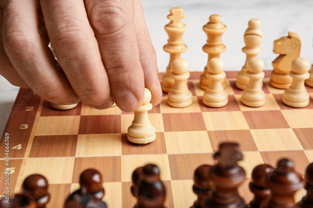 Man playing chess on light background, closeup Man playing chess on light background, closeup