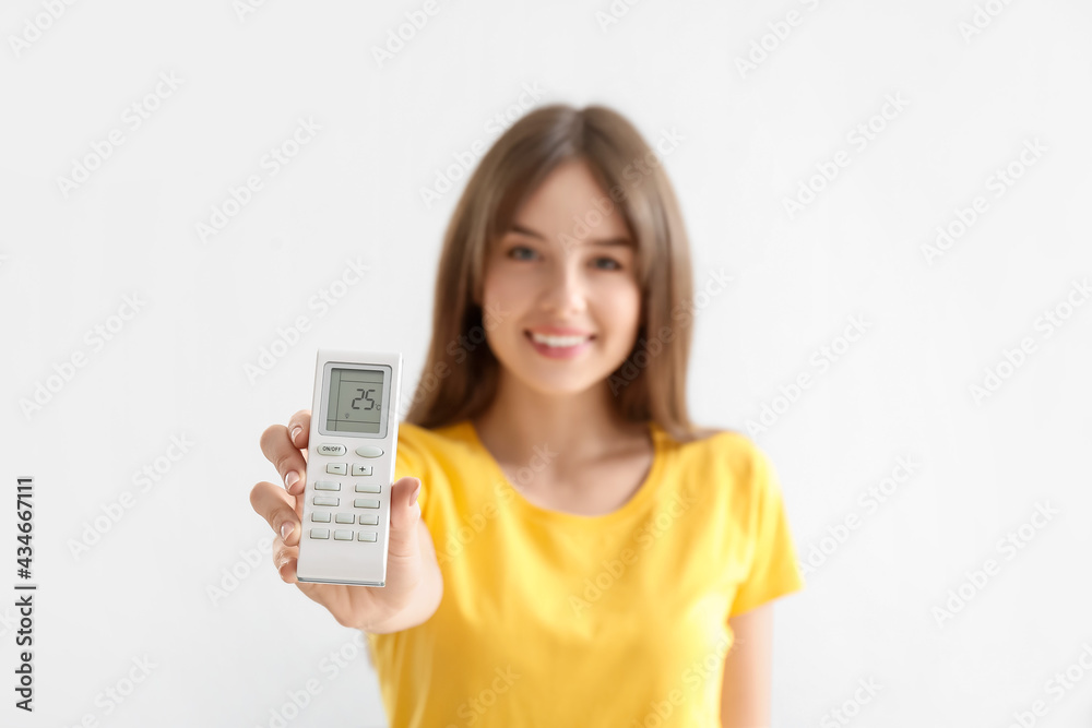 Young woman with air conditioner remote control on white background Young woman with air conditioner remote control on white background