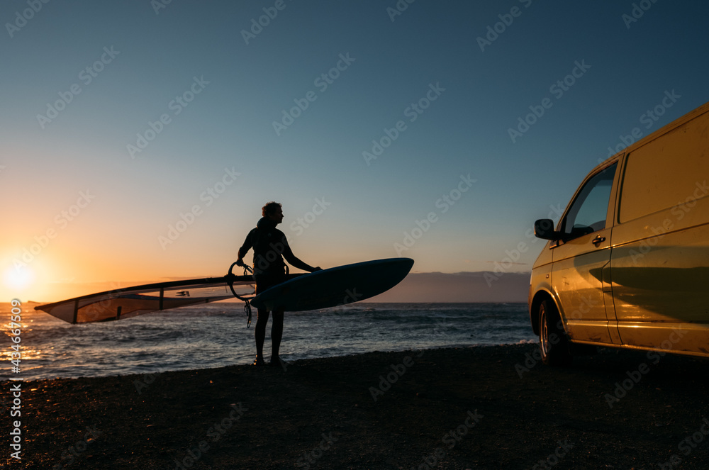 Surfer on the background of a colorful sunset and a surfmobile Surfer on the background of a colorful sunset and a surfmobile