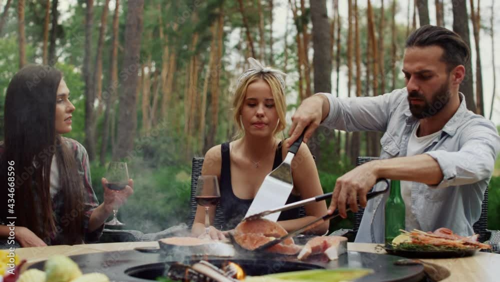 Serious guy making food on grill for bbq party outside. Guy using kitchen tools Serious guy making food on grill for bbq party outside. Guy using kitchen tools