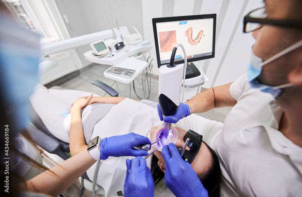 Close up of dentist and assistant using dental intraoral scanner while
