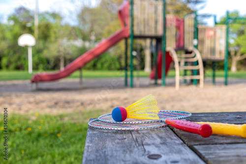 Fototapeta Naklejka Na Ścianę i Meble -  Badminton game rackets and shuttlecock on wooden table with playground in the park on a sunny summer day.