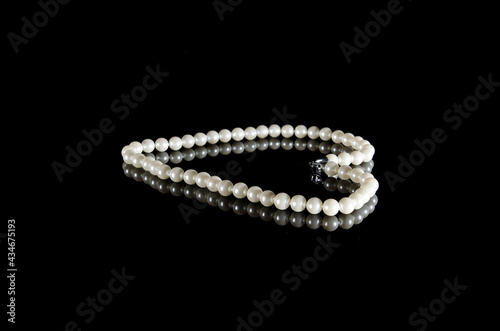 White pearls on black background with reflection