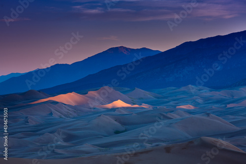 Dramatic landscape of last light hitting the peaks of the Colorado Sand Dunes under a colorful dusk skies.