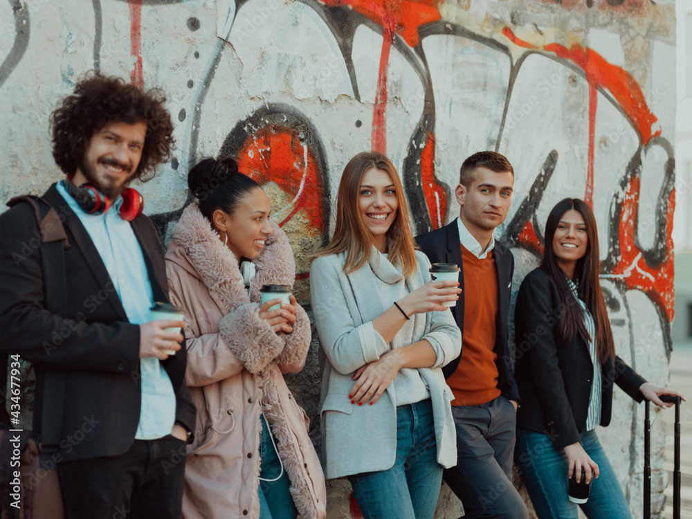 young people stand in front of a drawn wall in an abandoned street ...
