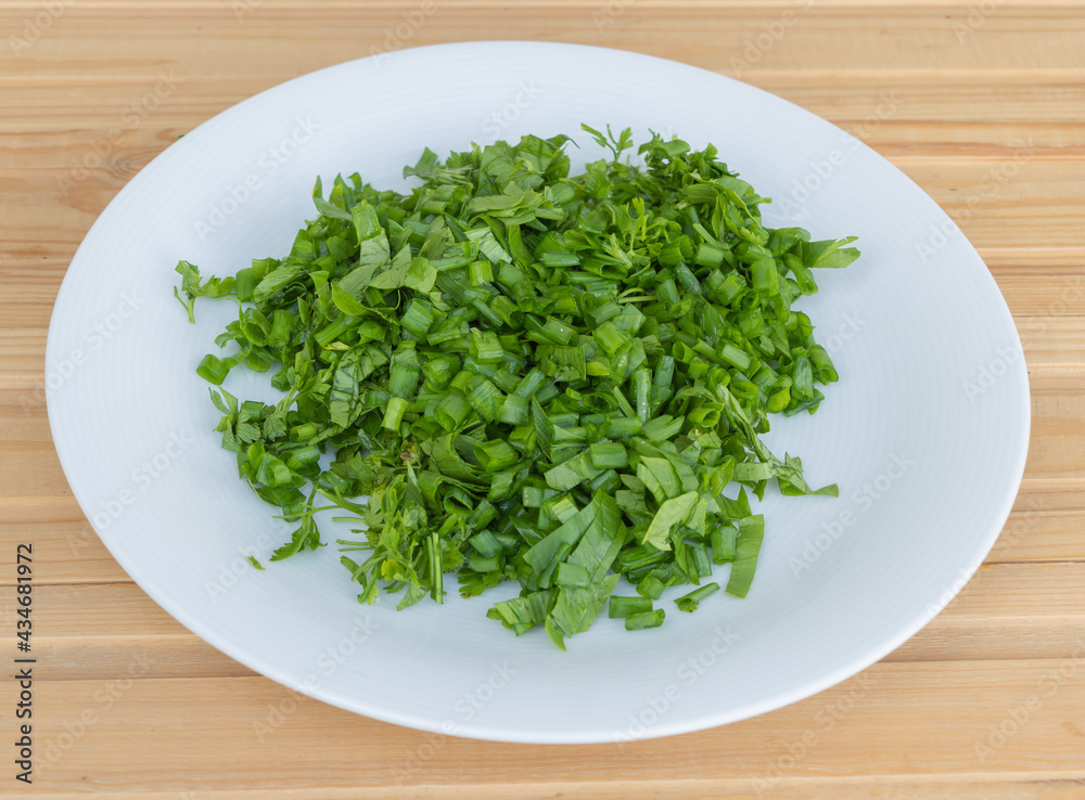 Sliced onion tails and parsley in a plate - recipe concept- in the process of cooking