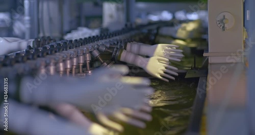 Close-up, rubber gloves are dipped in a special solution of liquid silicone. Modern manufacturing of medical gloves, conveyor line with liquid silicone. 4k, ProRes