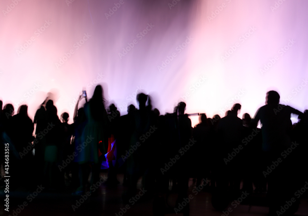 Silhouettes of people in motion near a colored fountain at night. Silhouettes of people in motion near a colored fountain at night.