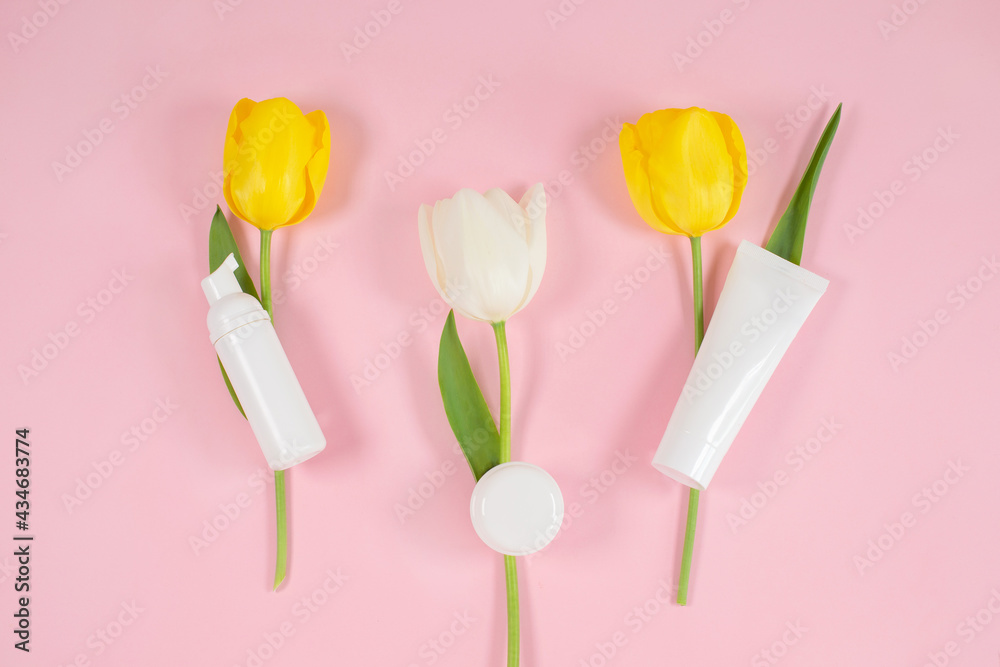 White cosmetic bottles containers on yelolow and white tulips flowers. White cosmetic bottles containers on yelolow and white tulips flowers.