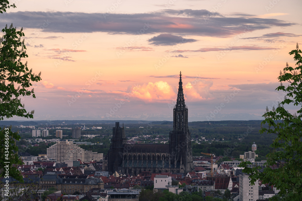 Sunset Panorma Mountain range alps with city ulm and ulmer minster take from a far distance at sunrise sunset dramatic spring sky and blooming tree