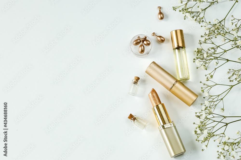top view of cosmetics in gold tones. lipsticks and perfumed oil on a white background, copy space top view of cosmetics in gold tones. lipsticks and perfumed oil on a white background, copy space