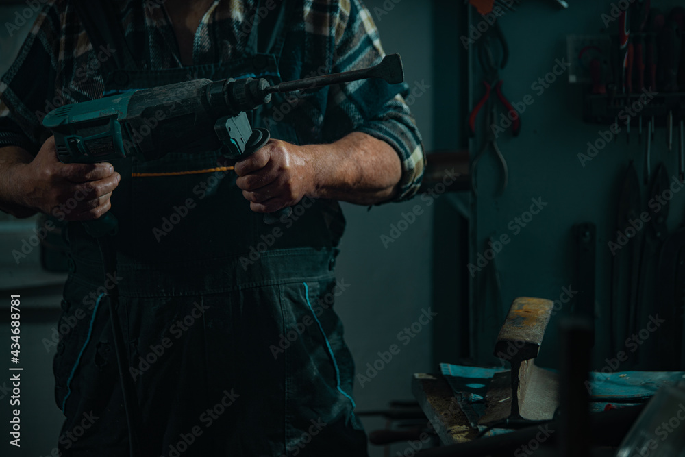 Elderly man with a tool works in a workshop