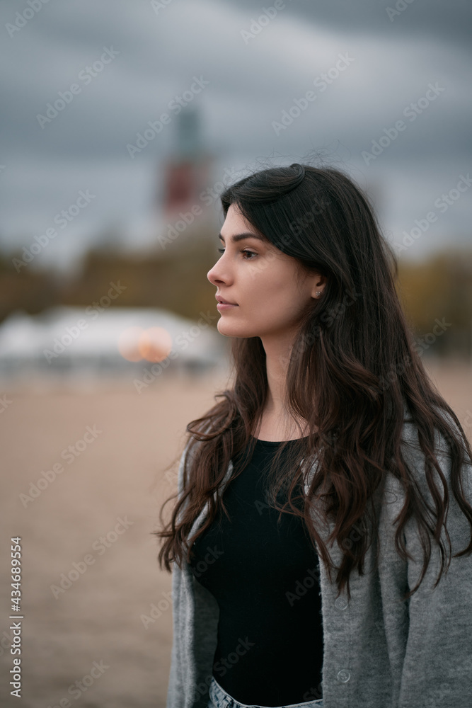 Sensual and gorgeous brunette on the beach. Clothed woman on the beach during autumn season on the seaside. Portrait of girl with brown hair wearing black shirt and jeans. Sensual and gorgeous brunette on the beach. Clothed woman on the beach during autumn season on the seaside. Portrait of girl with brown hair wearing black shirt and jeans.