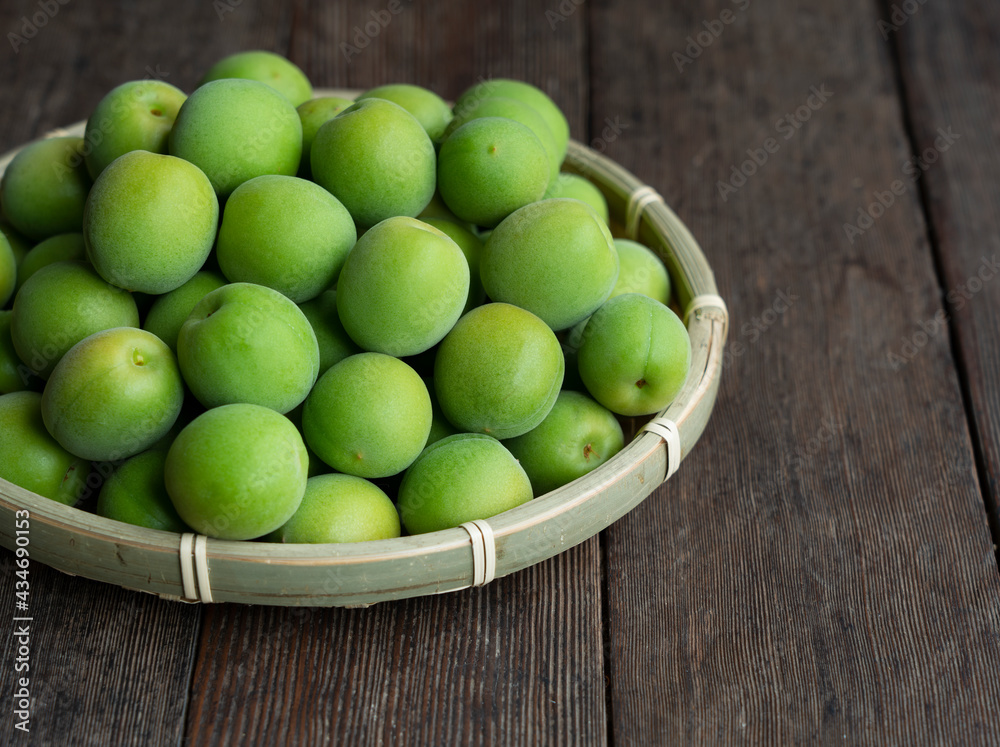 Plum fruit in a bamboo colander placed in the wooden background. Plum fruit in a bamboo colander placed in the wooden background.