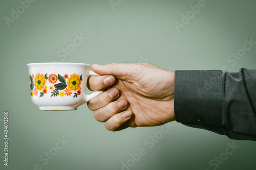 Männerhand mit Blümchen Kaffeetasse