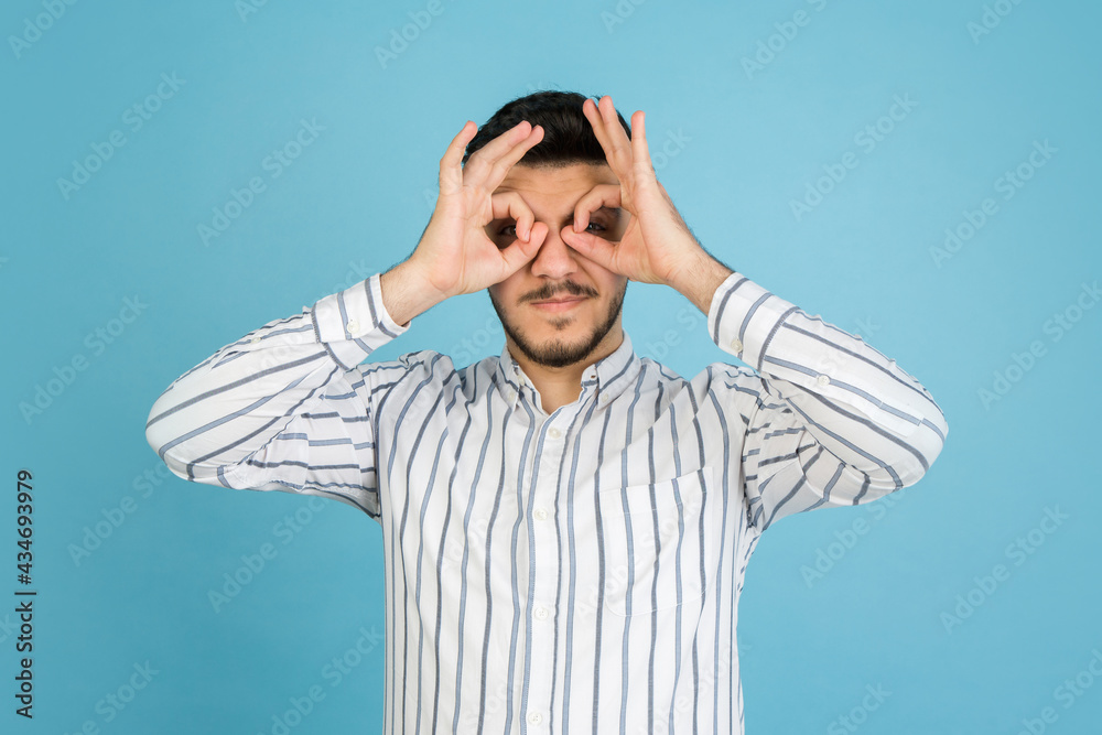 Young man's portrait on blue studio background. Concept of human emotions, facial expression, youth, sales, ad. Young man's portrait on blue studio background. Concept of human emotions, facial expression, youth, sales, ad.