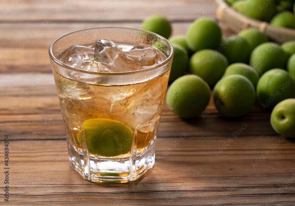 Plum wine and unripe plums on a wooden background.. Plum wine and unripe plums on a wooden background..