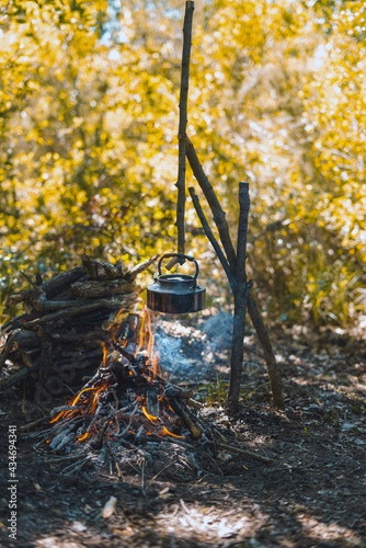 with knife, water bottle and titanium mug near the fire outdoors. bushcraft, adventure, travel, tourism and camping concept.
