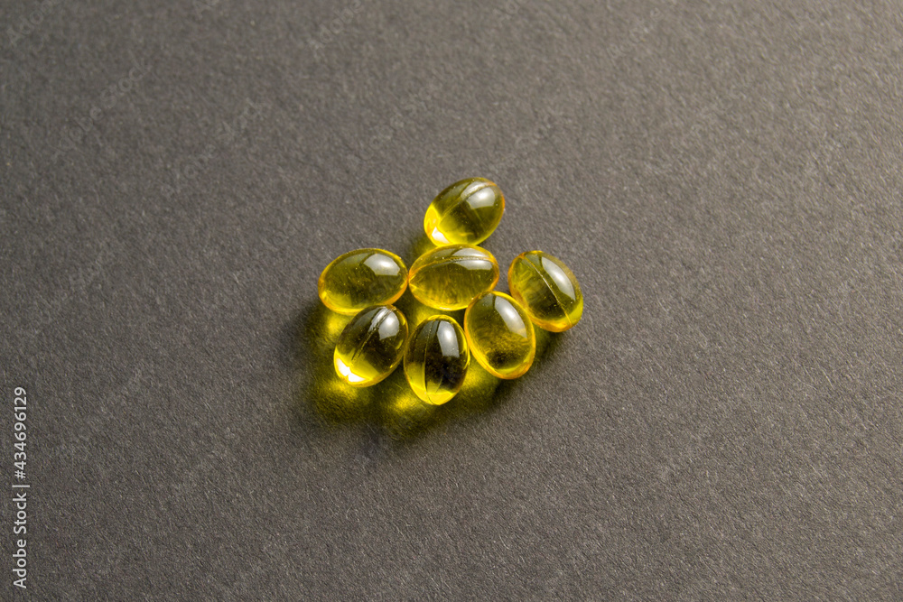 Yellow pills on a black background. treatment and prevention of diseases. Dietary supplement